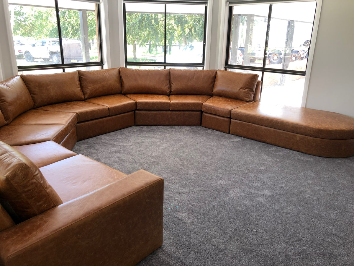Detail photograph of a caramel-coloured custom bay window lounge, showing the curved seating layout and rounded chaise end.