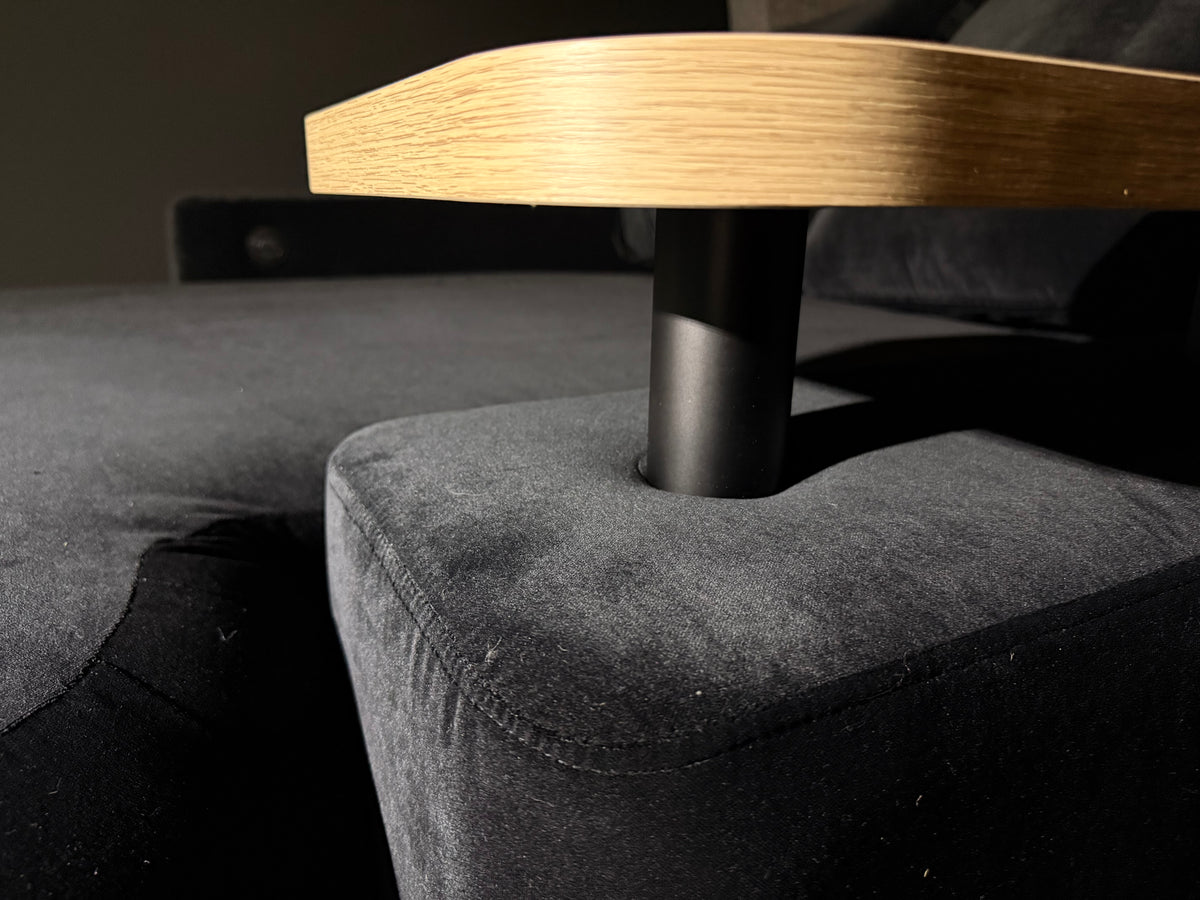 Close-up photograph of the custom DreamCloud floating timber table, with its dark upright entering the upholstered arm directly.