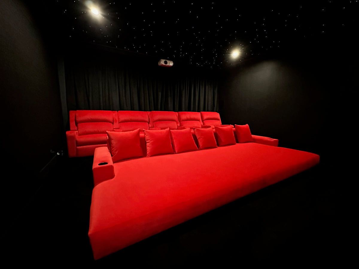 Red custom Dreamcoat daybed in a home theatre, with matching red cinema seats and a star-effect ceiling.