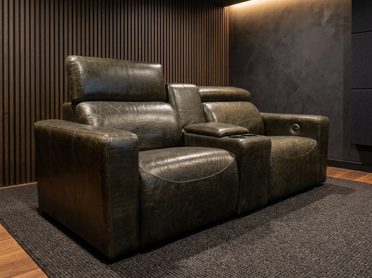 Three-quarter view of the Maximus leather electric recliner showing the power headrest raised to cinema viewing position and inner-arm control switch.